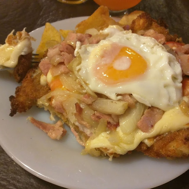 Suprema Brocal Milanesa Con Jamon Cebolla Tomate Tocino Huevo Y Guarnición de Papas Fritas